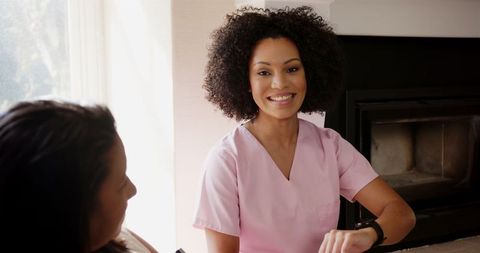 Nurse in pink scrubs using smartwatch in patient consultation