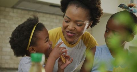 Smiling African American Mother with Daughters Enjoying Lunch at Home