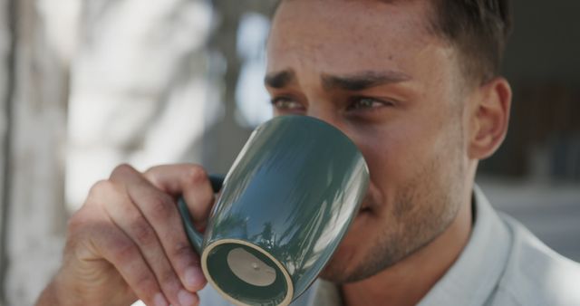 Young Man Drinking Coffee in Sunlit Outdoor Setting - Download Free Stock Images Pikwizard.com