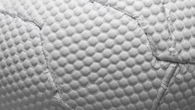 Honeycomb quilted mattress cover revealing stitched seams and frayed thread texture monochrome