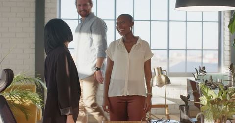 Multiracial team collaborating happily in bright office space