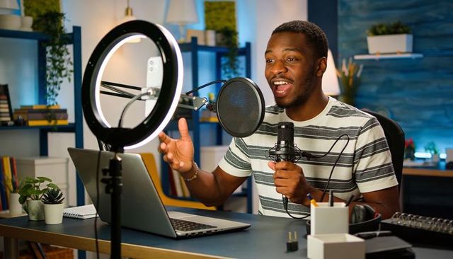 Podcaster hosting energetic live recording using microphone and ring light in home studio
