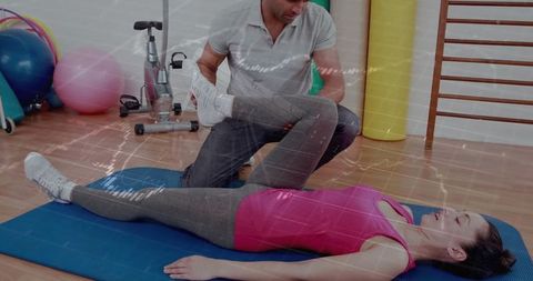 Therapist assisting female client in leg stretch on mat