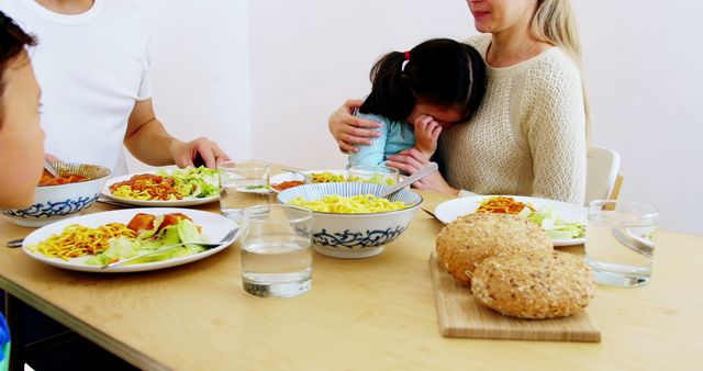 Family Having Dinner with Emotional Child Hugging Mother at Dining Table - Download Free Stock Images Pikwizard.com