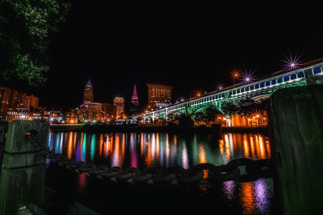 Beautiful downtown lights reflecting on river underneath bridge. Great for backgrounds showcasing night city life, urban landscape posters, tourism promotions, and editorial uses highlighting Cleveland's nighttime charm.