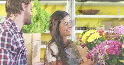 Woman florist in denim apron arranging vibrant yellow and pink bouquet at cozy boutique counter