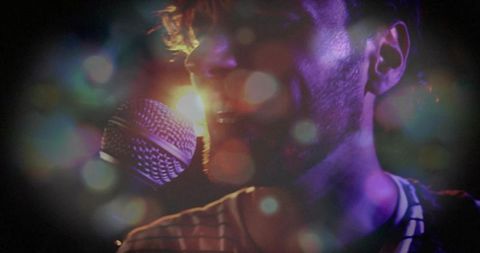 Male singer performing with cinematic backlight haze and bokeh, close-up microphone