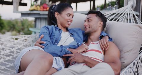 Biracial Couple Relaxing in Hammock by Beach