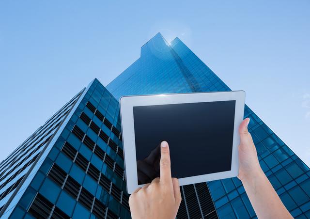 Digital composite of Holding tablet with skyscraper background