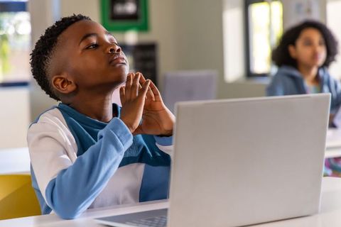 Focused African American Boy Using Laptop in Classroom Gazing Upward Modern Learning