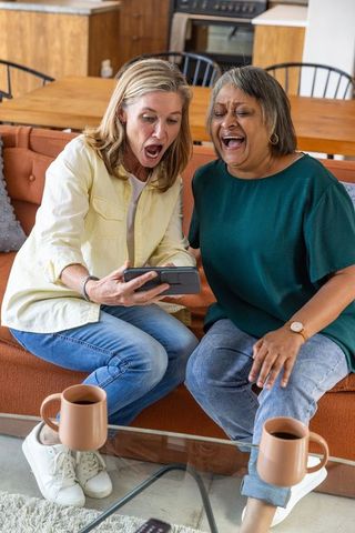 Senior Friends Laughing Together Viewing Smartphone on Sofa