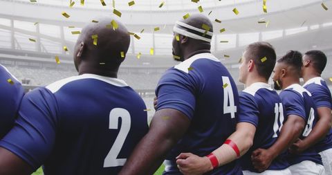Rugby players hugging on a pitch while golden confetti falls, symbolizing their recent victory. Ideal for promoting teamwork in sports, advertising athletic apparel, or articles on sportsmanship and unity.