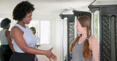 Friendly Fitness Trainer Greeting Client in Modern Gym