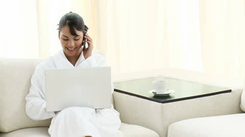 Woman Relaxing at Home Using Laptop and Phone in Bathrobe
