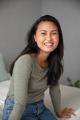 Asian Woman Enjoying Relaxed Moment in Cozy Modern Bedroom