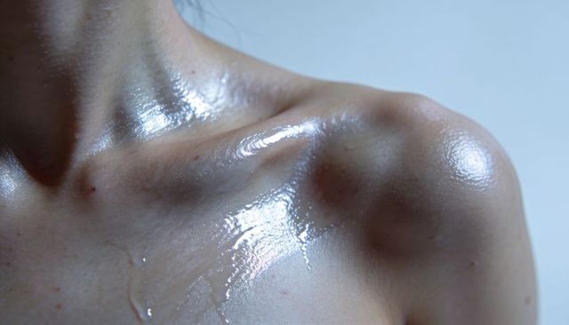 Glistening collarbone and shoulder with glossy liquid, closeup skin texture and freckles
