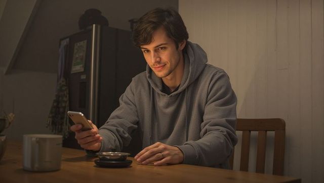 Young man checking smartphone at dining table wearing gray hoodie showing wedding ring