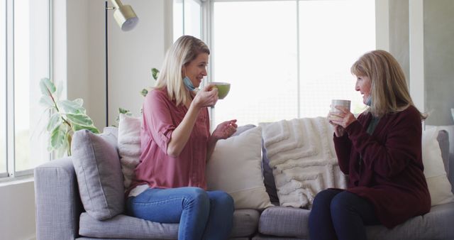 Two Women Sitting on Couch Enjoying Coffee at Home - Download Free Stock Images Pikwizard.com