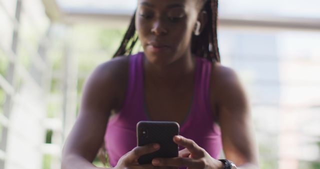 Woman working out while looking at her smartphone, illustrating technology use in fitness routines. This can be used in articles discussing exercise trends, fitness apps, or how technology aids in maintaining healthy lifestyle habits.