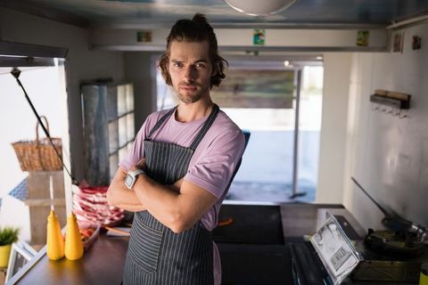 Confident food vendor smiling in food truck with folded arms