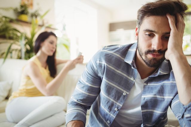 Upset couple ignoring each other on sofa in living room