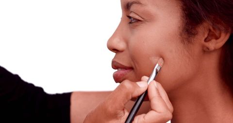 Makeup Artist Applying Foundation to Model on White Background