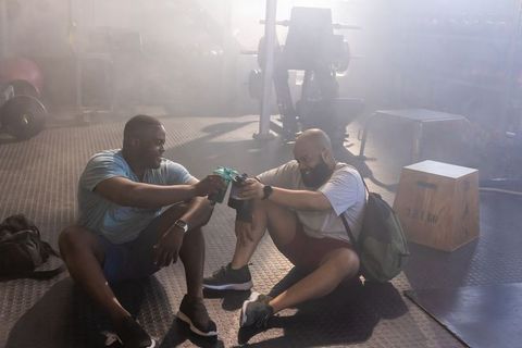 African american men toasting shaker bottles after intense gym workout for recovery