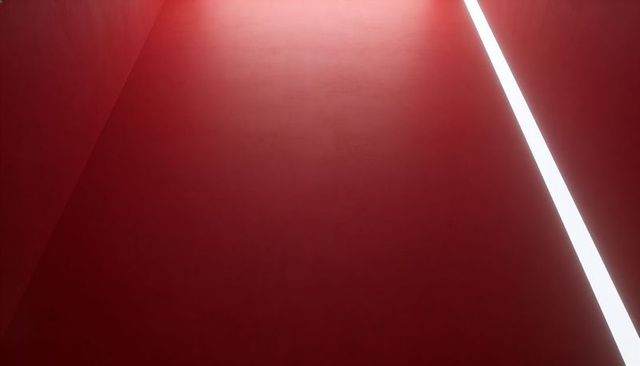 Minimalist crimson corridor with diagonal led light and dramatic negative space
