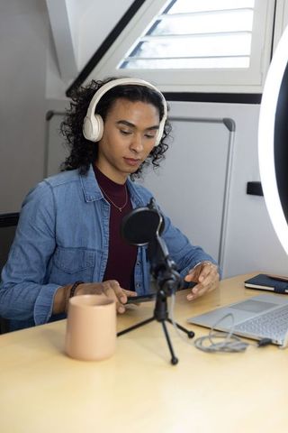 Non-binary creator preparing podcast livestream setup in loft studio with headphones
