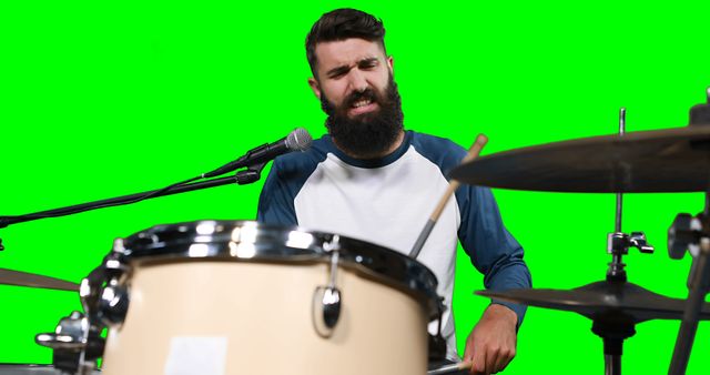 Male drumer playing drum against green screen