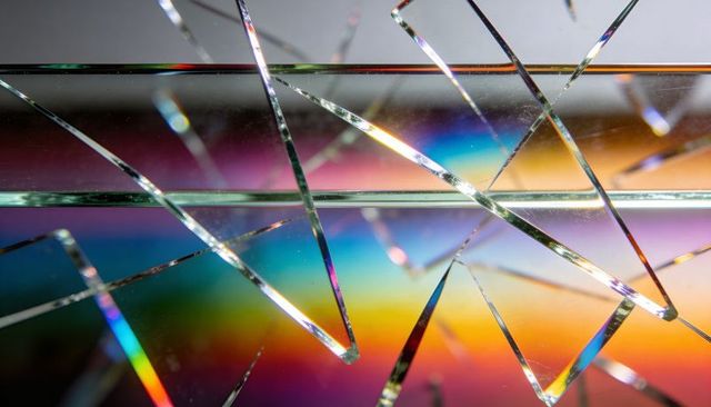 Shattered glass catching prism light over iridescent rainbow spectrum macro close-up studio