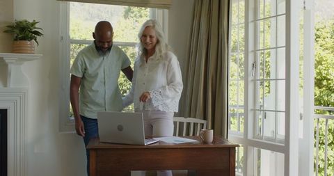 Senior Couple Smiling by Laptop at Home