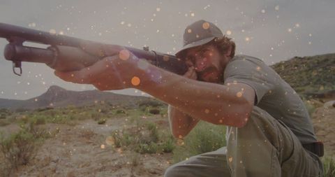 Hunter crouching in desert aiming shotgun with sparkle overlay