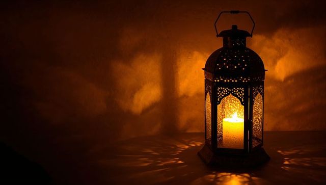 Ornate filigree lantern casting warm patterned shadows with glowing pillar candle