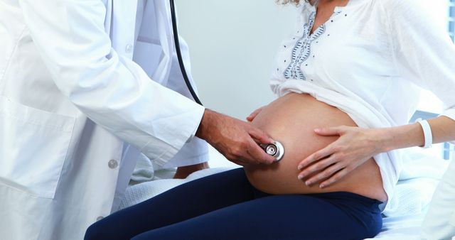 A Caucasian doctor is performing an ultrasound on the belly of a pregnant Caucasian woman, with copy space. This prenatal check-up is crucial for monitoring the health and development of the baby.