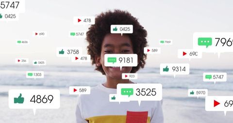 Smiling black boy standing at ocean beach surrounded by social media notification icons