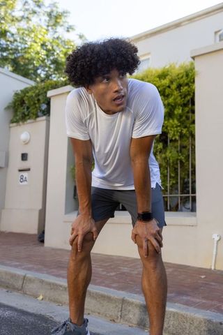 Active Man Resting After Urban Run Wearing Fitness Tracker