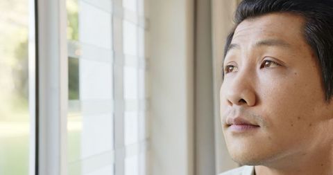 Pensive Asian Man Relaxing Near Bright Window