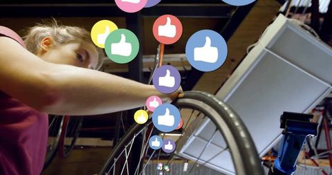 Mechanic aligning bicycle wheel with floating like icons in workshop