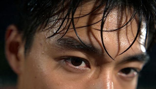 Extreme close-up of sweaty young asian male showing perspiration, wet hair and intense gaze