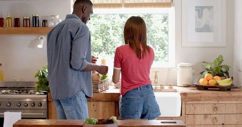 Couple cleaning fresh vegetables in rustic kitchen together