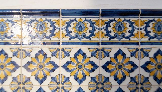 Hand-painted blue yellow ceramic wall tiles featuring floral rosette pattern and glossy border