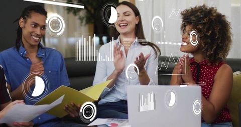 Multiracial team clapping during analytics review with laptop, folder and digital charts