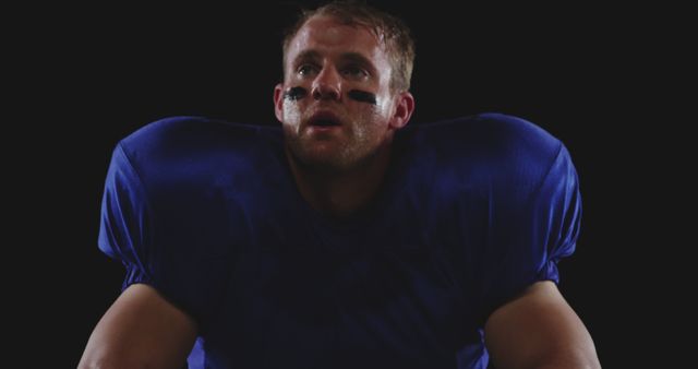 Focused Football Player in Blue Jersey with Face Paint in Dark Background - Download Free Stock Images Pikwizard.com