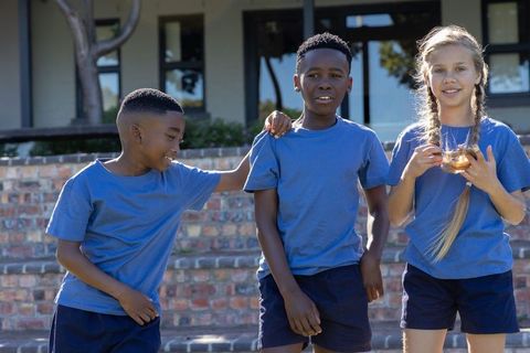 Children wearing matching blue shirts standing on brick steps sharing playful moment