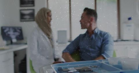 Female doctor wearing hijab consulting male patient in dental clinic with instrument tray