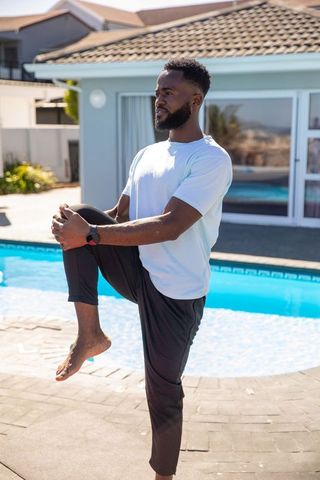 Outdoor Fitness: Man Stretching Beside Pool in Bright Sunlight