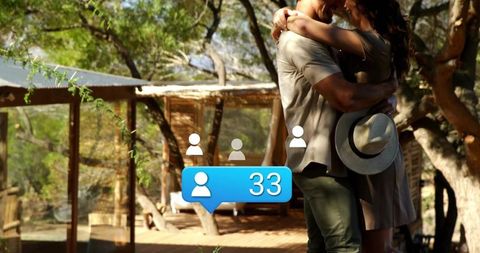 Couple embracing on rustic cabin deck with wide-brim hat and social notification bubble