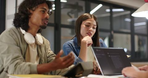 African American Coworkers Discussing Code on Laptop in Modern Office Brainstorming