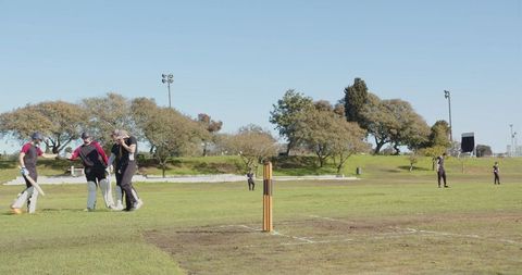 Cricket Team Strategizing During Sunny Day Match